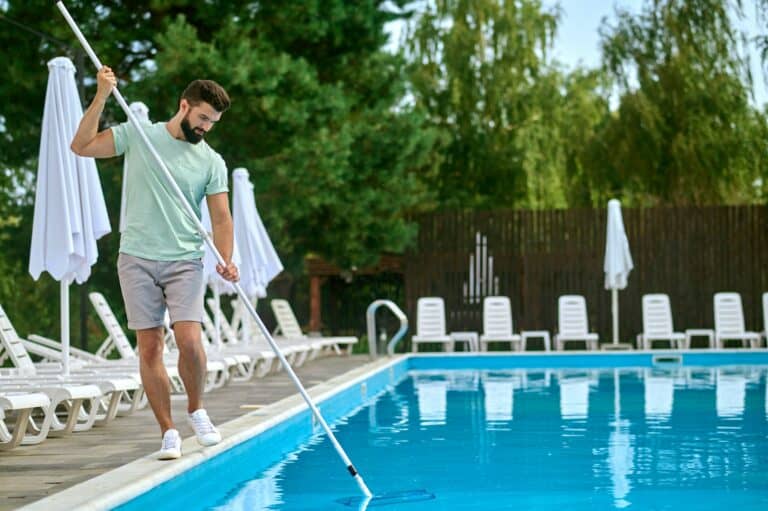 A service person cleaning the swimming pool and looking busy