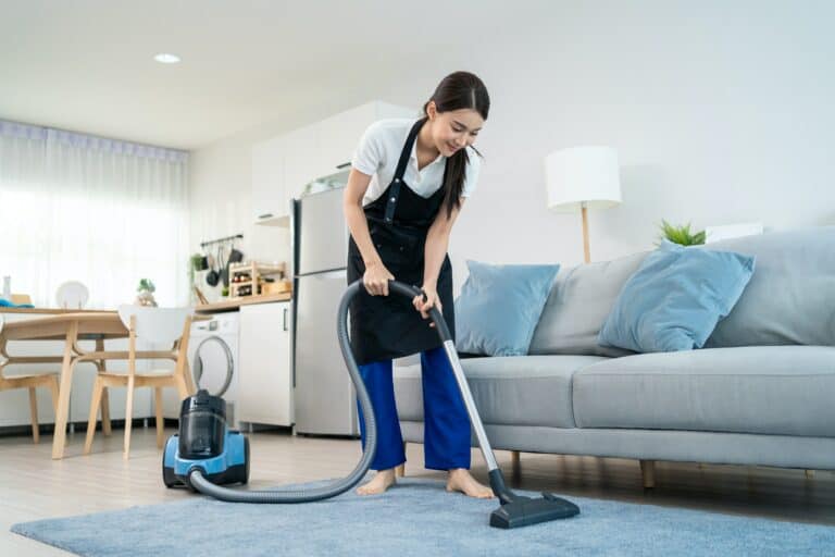 Asian cleaning service woman worker cleaning in living room at home.