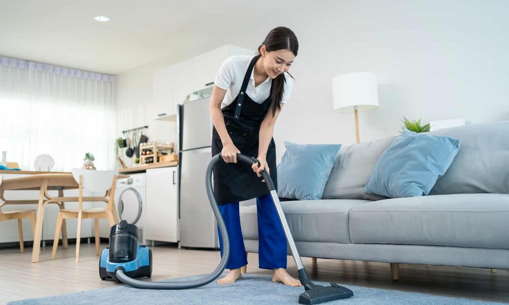 Asian cleaning service woman worker cleaning in living room at home.