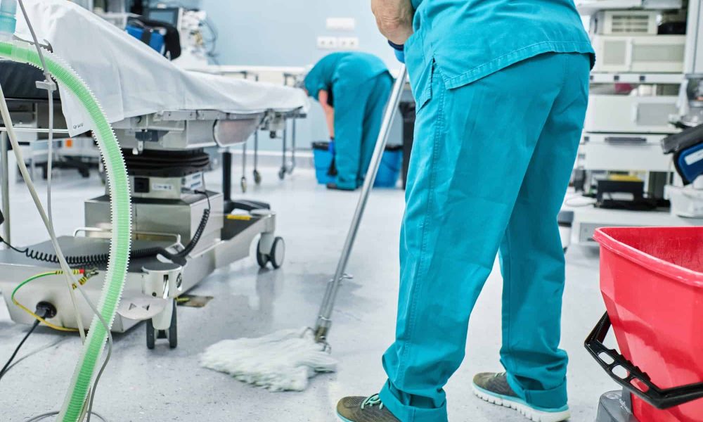 woman cleaning staff mopping the floor of a hospital operating room