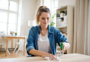 Young woman indoors at home, cleaning table.